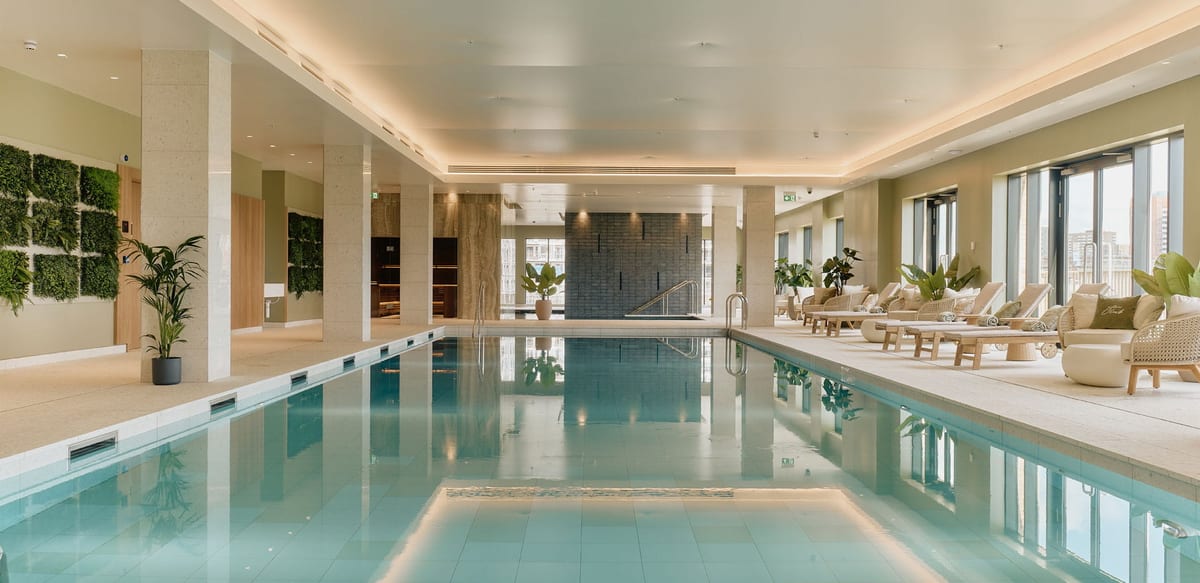 The 20 m pool at The Riverside Club, with loungers along tall windows and planted green walls