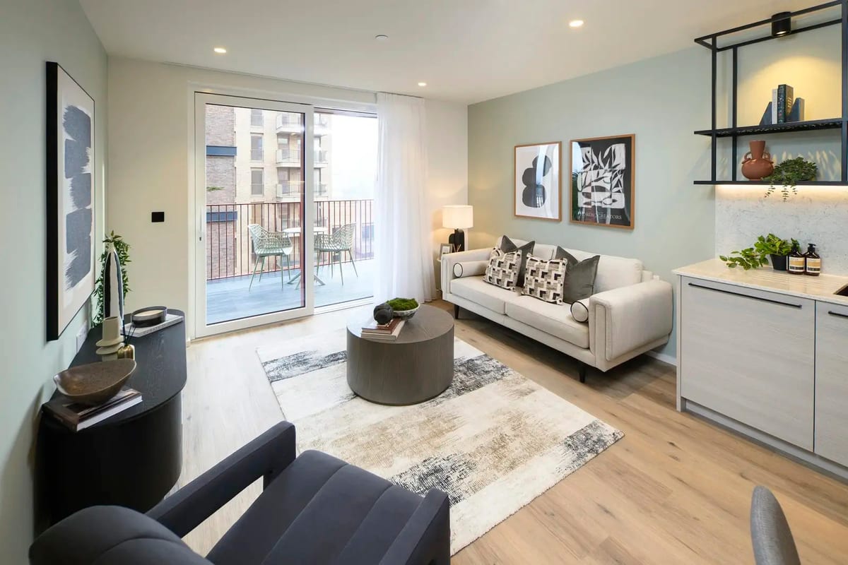 Show apartment living room with a cream sofa, patterned cushions, a round coffee table and sliding doors to the balcony